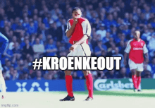 a soccer player stands on a field with #kroenkeout written on the bottom