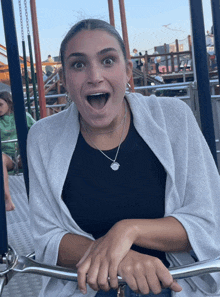 a woman wearing a black shirt and a silver necklace is sitting on a swing with her mouth open