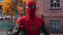 a man in a spiderman costume is pointing at the camera