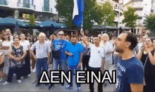 a man is holding a flag in front of a crowd and the words aen einai are on the bottom