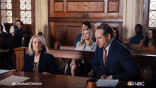 a man in a suit and tie sits at a table in a courtroom with nbc written on the bottom of the screen