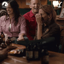 a group of people are sitting at a table with bottles of beer and a paramount network logo in the background