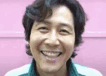 a close up of a man smiling against a pink wall .