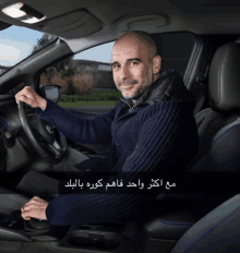 a man in a blue sweater is sitting in a car with arabic writing on it