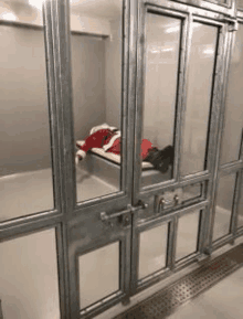 a man in a santa suit is sleeping in a cell in a jail .