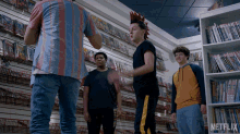 a group of young men standing in front of a wall of books with netflix written on the bottom right