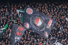 a crowd of people in a stadium with a flag that says ' feyenoord ' on it