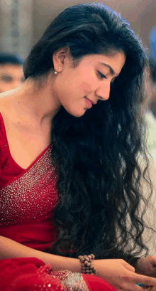 a woman with long hair is wearing a red top and a bracelet