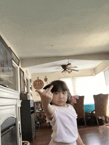 a little girl in a living room with a sign on the wall that says " eat "