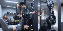 a man helps a woman lift a barbell in a gym with a sign in the background that says carb dien