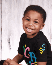 a young boy wearing a black shirt with the letters ch on it smiles