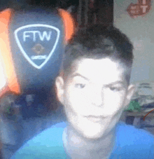 a man in a blue shirt is looking at the camera in front of a ftw logo .