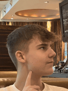 a young man is sitting in front of a sign that says ' sell us ' on it