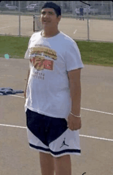 a man wearing a white t-shirt and black shorts is standing on a basketball court