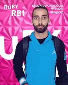 a man in a blue jacket is standing in front of a pink background that says ruby rb1 salon du chocolat nyc 2019