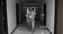 a man with a bandage on his chest is walking down a hallway .