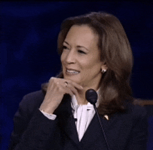 a woman in a suit is smiling while talking into a microphone