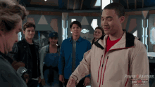 a group of people are standing in a room with a power rangers logo in the corner