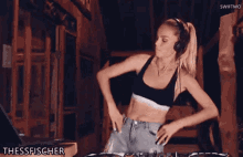 a woman wearing headphones and a calvin klein top is dancing in front of a dj