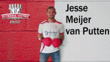 a man wearing boxing gloves stands in front of a red and white wall with the name jesse meijer van putten on it