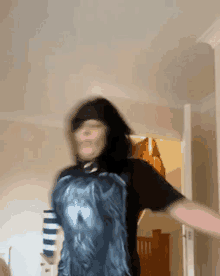 a woman in a black t-shirt is dancing in a room with her arms outstretched .