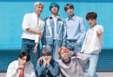 a group of young men are posing for a picture in front of a blue brick wall