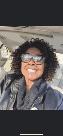 a woman with curly hair wearing sunglasses and a sweater