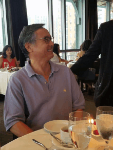 a man wearing a blue shirt with a bee on it sits at a table