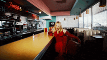 a woman in a red dress sits at a counter in a diner with a sign that says tasty coffee