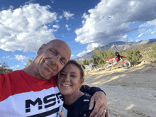 a man and woman are posing for a picture with a motorcycle in the background