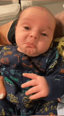 a baby wearing a blue pajamas with the word roar on it