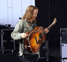 a man with long hair is playing a guitar with a patch on his shirt that says ' tiger ' on it