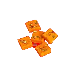 a bunch of orange squares with nuts on top of them