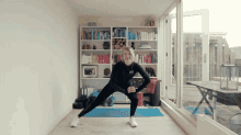 a woman is doing squats in front of a bookshelf that has a book titled ' a woman 's guide '