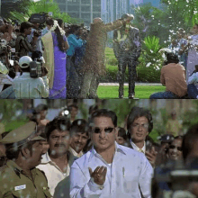 a man wearing sunglasses is standing in front of a crowd of people taking pictures of him .