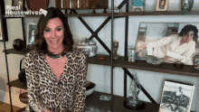 a woman in a leopard print shirt is standing in front of a shelf with a picture of michael jackson