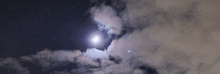 a full moon shines through the clouds in a dark sky