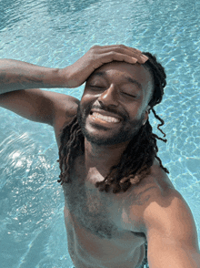 a shirtless man is taking a selfie in a pool