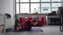 a woman is doing exercises on a yoga mat in front of a red couch with a sign that says " no smoking "