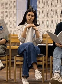 a woman sits in a chair reading a newspaper which says ' swedish ' on it