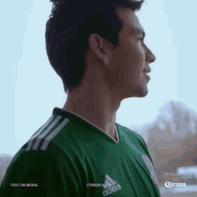 a man is wearing a green adidas jersey and looking out a window .