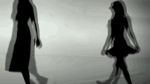 two silhouettes of women are standing next to each other on a white surface .