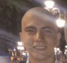 a close up of a man 's face with a bald head and a smile .