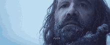 a man with a beard and long hair is standing in the snow and saying `` fuck '' .