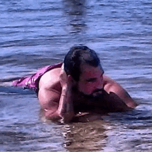 a man with a beard is laying on his back in the water .