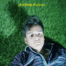 a young man is laying on the grass with the name pradeep kumar written above him