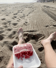 a person laying on the beach with a tray of ground beef