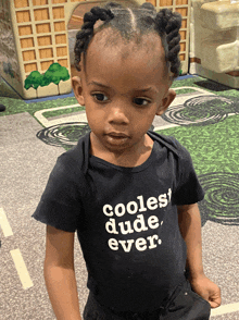 a little boy wears a black shirt that says coolest dude ever