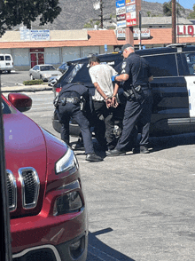 a man is being handcuffed by police officers in front of a liquor store