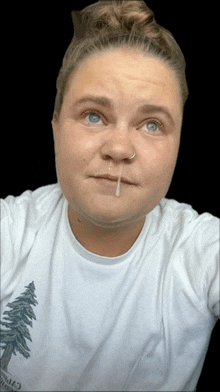 a woman wearing a white shirt with a pine tree on it is taking a selfie